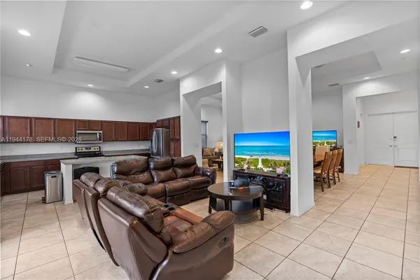 a living room with stainless steel appliances furniture a rug and a kitchen view