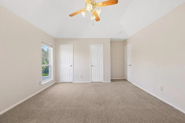 an empty room with windows and chandelier fan