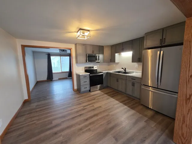 a kitchen with stainless steel appliances granite countertop a refrigerator a sink dishwasher and a stove with wooden floor