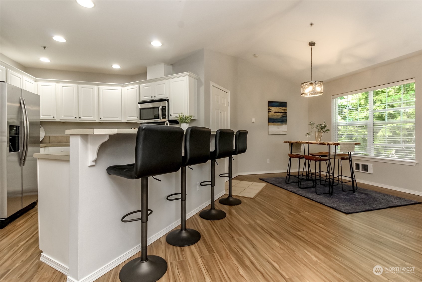 1607 Kincaid Street, Unit E8 DuPont, WA 98327 - Photo 6 of 28 a kitchen with stainless steel appliances granite countertop a stove top oven a refrigerator a dining table and chairs with wooden floor