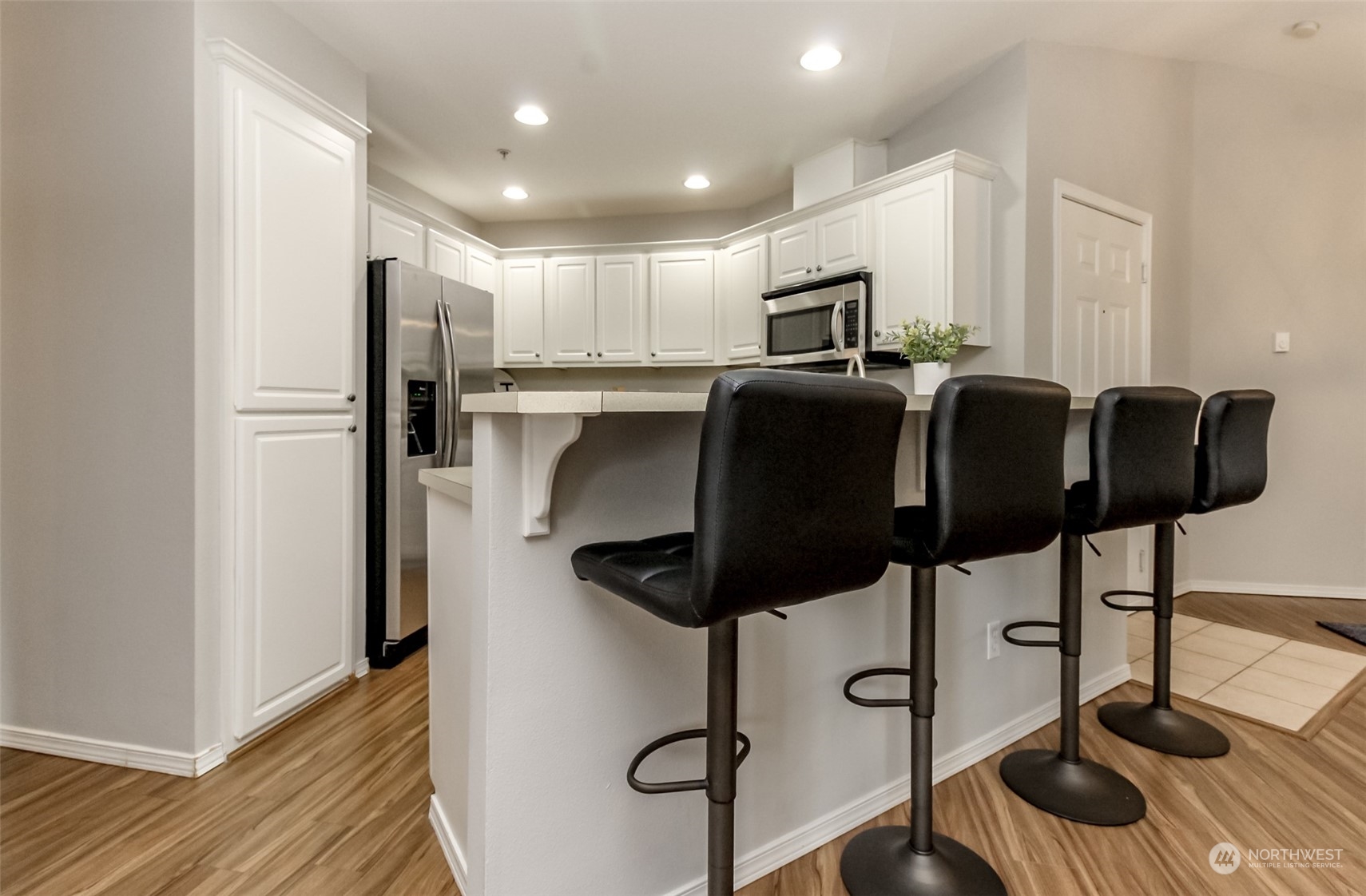 1607 Kincaid Street, Unit E8 DuPont, WA 98327 - Photo 10 of 28 a kitchen with stainless steel appliances granite countertop a refrigerator a stove a microwave oven with white cabinets and wooden floor