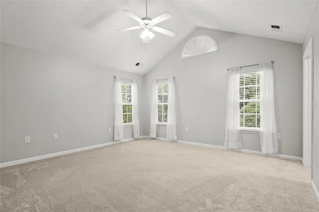 an empty room with chandelier fan and windows