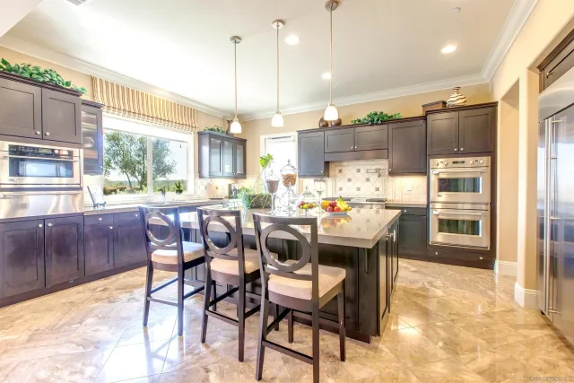 a kitchen with stainless steel appliances kitchen island granite countertop a table chairs and a refrigerator