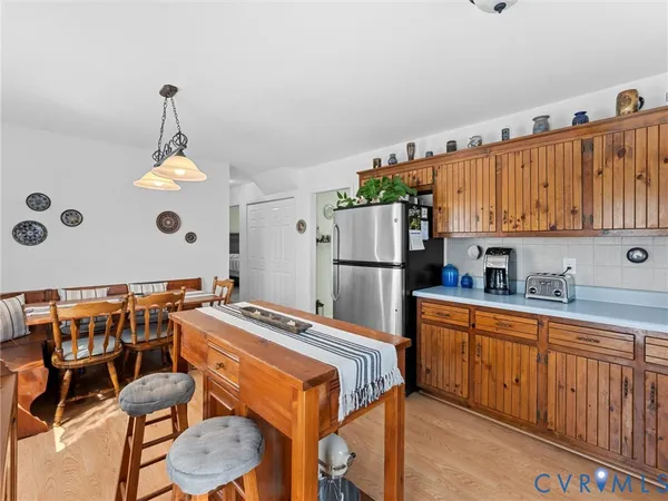 a kitchen with stainless steel appliances granite countertop a refrigerator a sink dishwasher a stove and a dining table with wooden floor