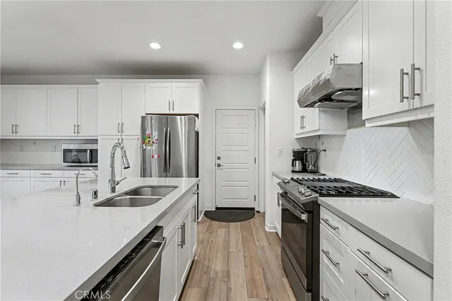 a kitchen with sink a stove and white cabinets