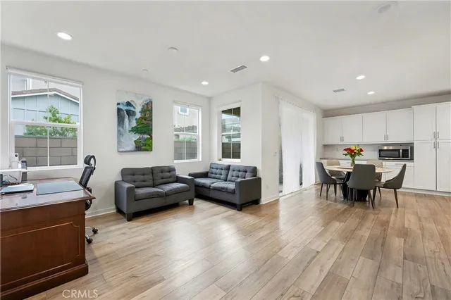 a living room with furniture and kitchen view with wooden floor