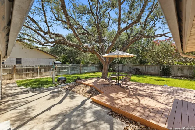 a view of a backyard with table and chairs under an umbrella
