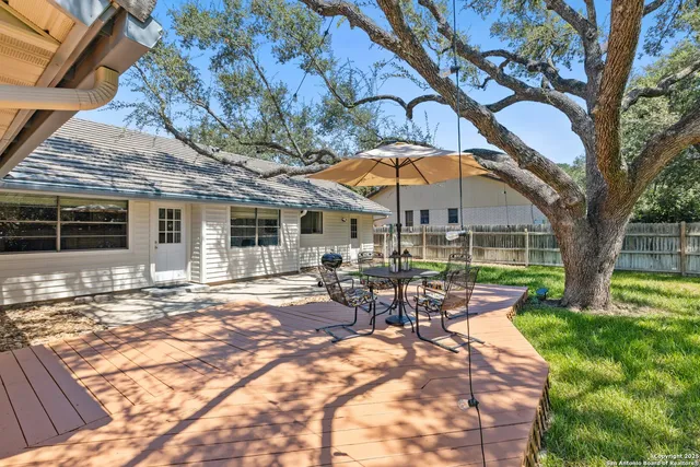 a view of a backyard with table and chairs under an umbrella