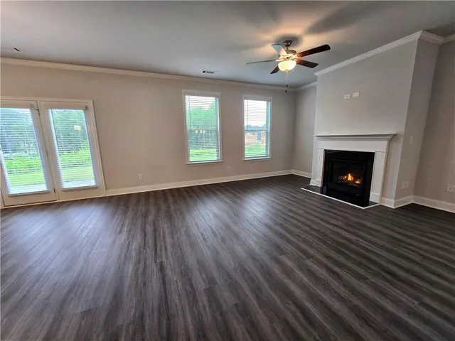 an empty room with wooden floor fireplace and windows