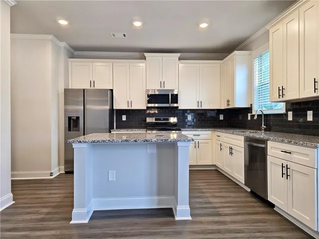 a kitchen with stainless steel appliances granite countertop a stove a sink and white cabinets