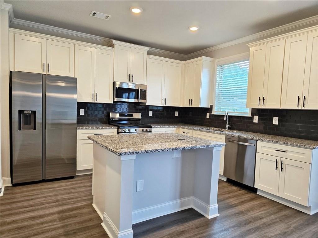 3856 Lockaby Way Lawrenceville, GA 30044 - Photo 17 of 36 a kitchen with stainless steel appliances granite countertop a stove a sink a refrigerator a white cabinets and wooden floor