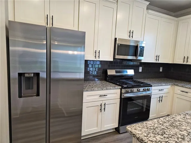 a kitchen with stainless steel appliances granite countertop a stove a refrigerator and a microwave