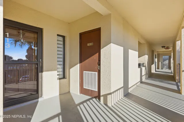 a view of a hallway with wooden floor and a bathroom