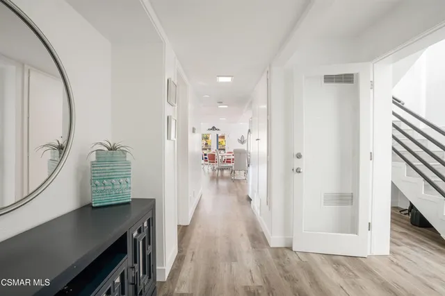 a view of a hallway to a livingroom with wooden floor and furniture
