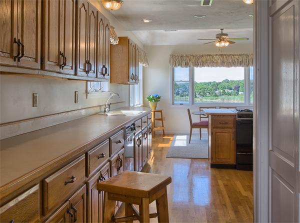 32 Surfside Road Scituate, MA 02066 - Photo 2 of 18 a kitchen with stainless steel appliances granite countertop a refrigerator a sink dishwasher a stove and a dining table with wooden floor