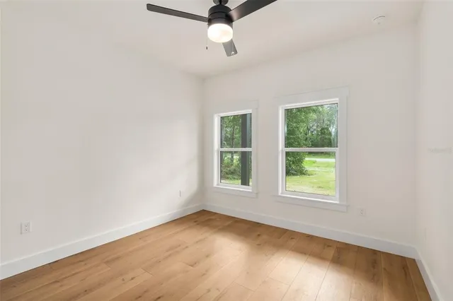 an empty room with a window and a ceiling fan