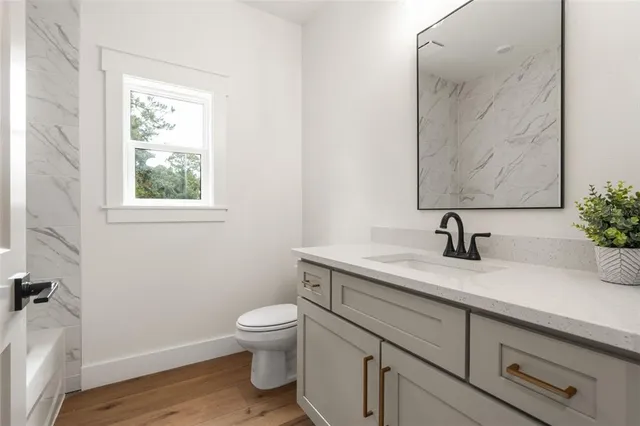 a bathroom with a granite countertop sink mirror vanity and toilet