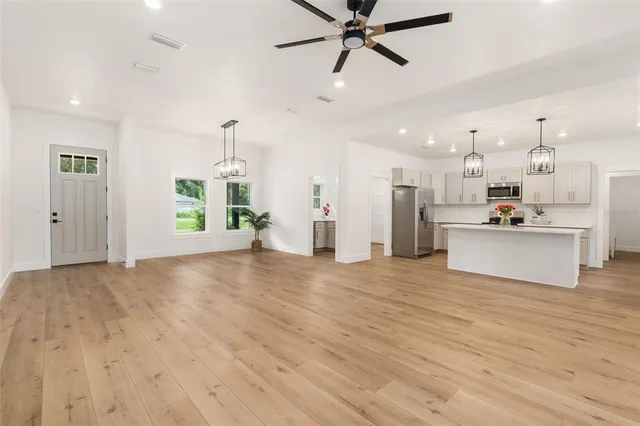a view of a kitchen with kitchen island a refrigerator wooden floor and a dining table