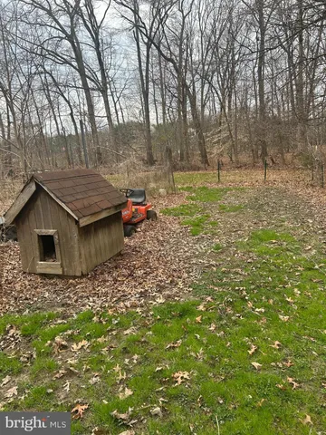 a backyard of a house with large trees and wooden fence