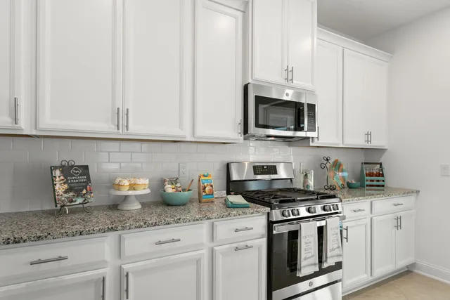 a kitchen with granite countertop white cabinets and a stove top oven with granite countertops