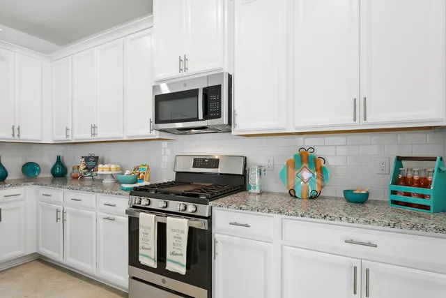 a kitchen with granite countertop white cabinets and stainless steel appliances