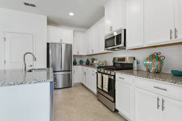 a kitchen with stainless steel appliances granite countertop a refrigerator sink stove microwave and cabinets
