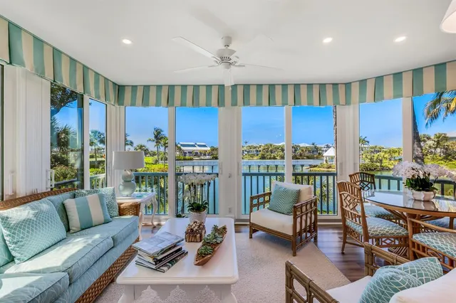 a living room with furniture a large window and a potted plant