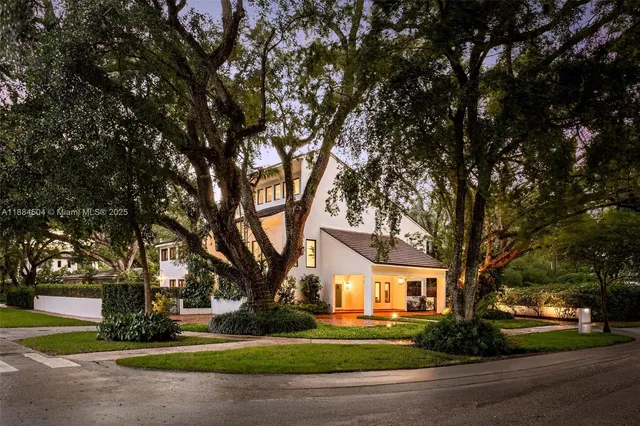 a tree in front of a brick house next to a yard