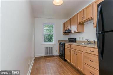 2978 Cornwall Road Dundalk, MD 21222 - Photo 23 of 27 a kitchen with granite countertop a refrigerator a sink dishwasher a stove and white countertops with wooden floor