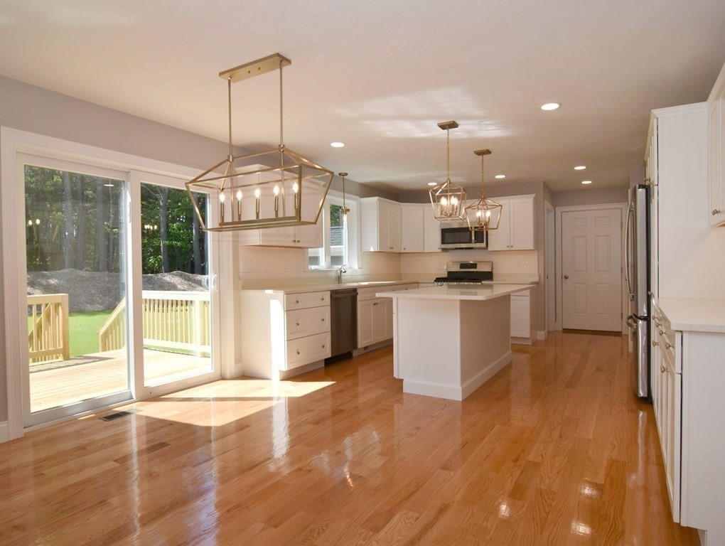 881 Maple Street Mansfield, MA 02048 - Photo 10 of 34 a kitchen with stainless steel appliances kitchen island granite countertop a refrigerator a stove a sink and a dining table with wooden floor