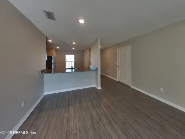 a view of a big room with wooden floor and kitchen