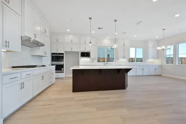 a large kitchen with stainless steel appliances kitchen island granite countertop a large counter top a sink a stove and a cabinets