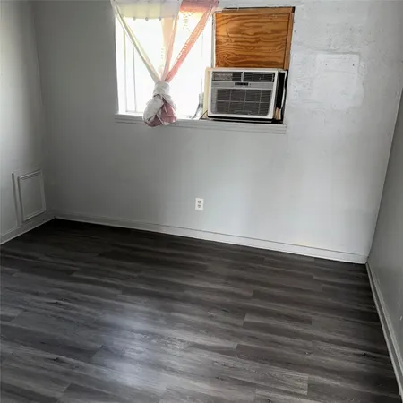 a view of empty room with wooden floor and window