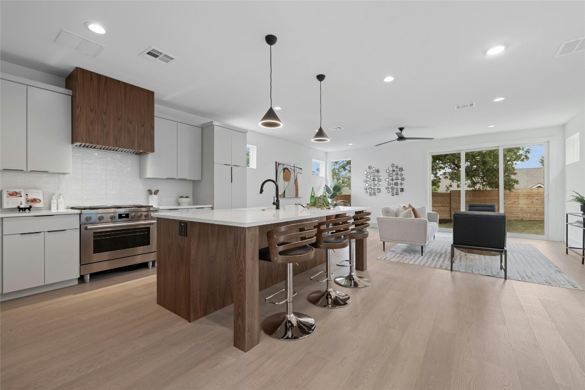 a kitchen with stainless steel appliances kitchen island granite countertop a stove top oven a sink a dining table and chairs with wooden floor