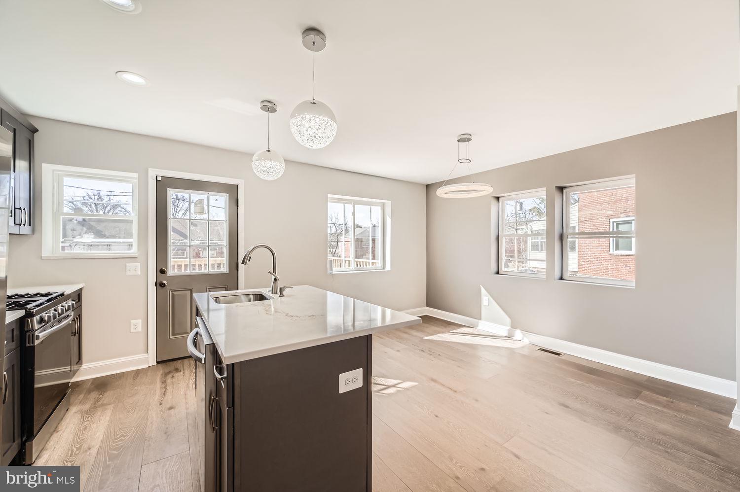 801 Bradhurst Road Baltimore, MD 21212 - Photo 12 of 26 a hall with kitchen island a sink wooden floor and a large window