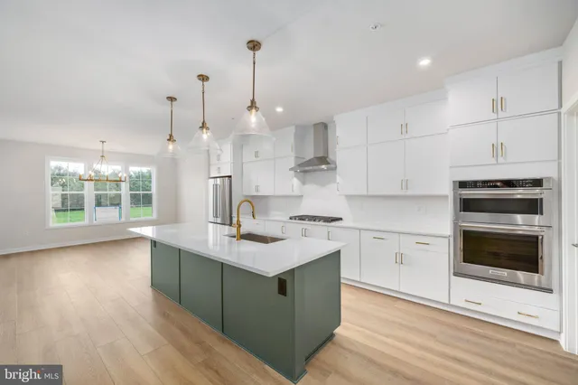 a kitchen with stainless steel appliances granite countertop a sink a stove and a wooden floors