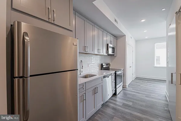 a kitchen with stainless steel appliances a refrigerator a sink and white cabinets