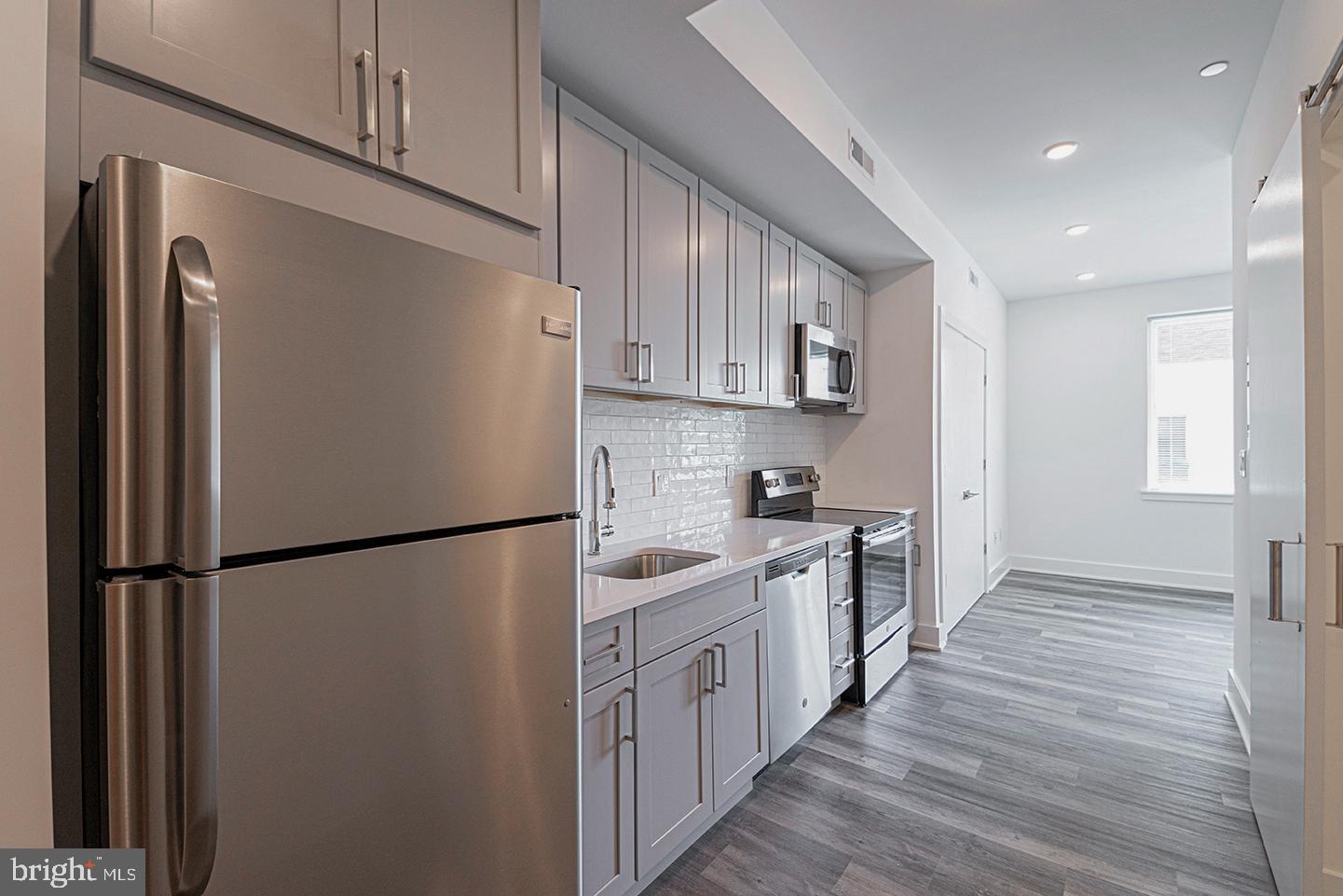 1245 Ridge Avenue, Unit 103 Philadelphia, PA 19123 - Photo 1 of 18 a kitchen with stainless steel appliances a refrigerator a sink and white cabinets
