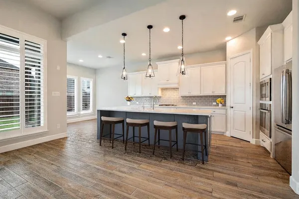 a kitchen with stainless steel appliances granite countertop a table chairs stove a sink and a refrigerator