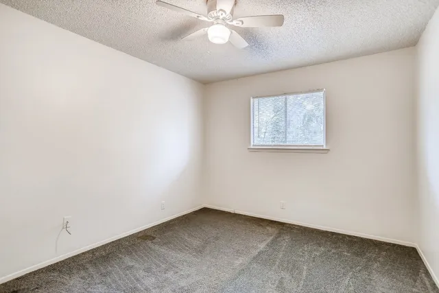 an empty room with a fan & a window