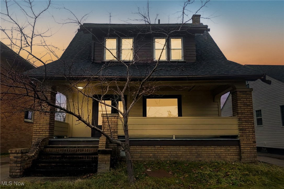 View of front of house with a porch, roof with shingles, and a chimney