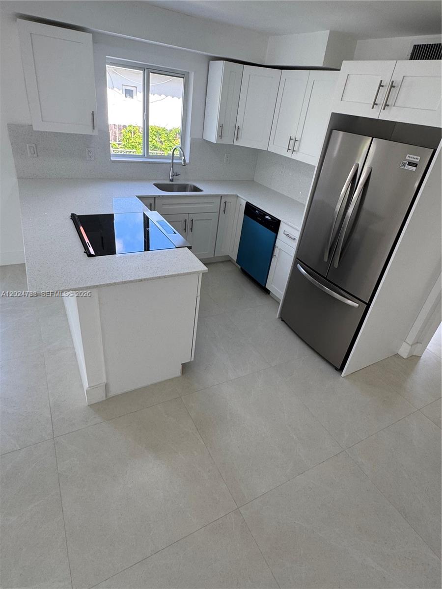3305 Southwest 28th Street, Unit 3305 Miami, FL 33133 - Photo 7 of 17 a kitchen with stainless steel appliances a refrigerator sink and white cabinets