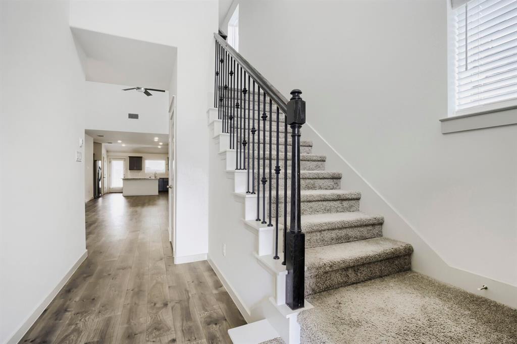 1368 Cedar Street Forney, TX 75126 - Photo 5 of 29 Carpeted staircase with black iron balusters, wood-finish flooring, white walls, and a ceiling fan