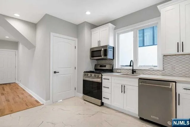 a kitchen with cabinets stainless steel appliances and sink