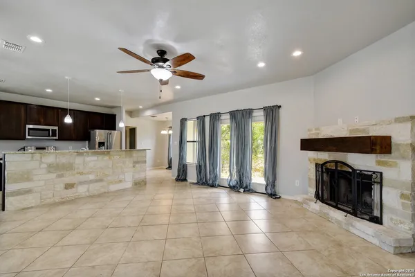 a view of an empty room and kitchen with fireplace fan