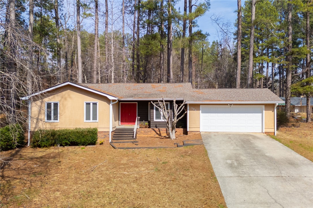 This cozy home offers a welcoming facade with a classic garage and lush surroundings.