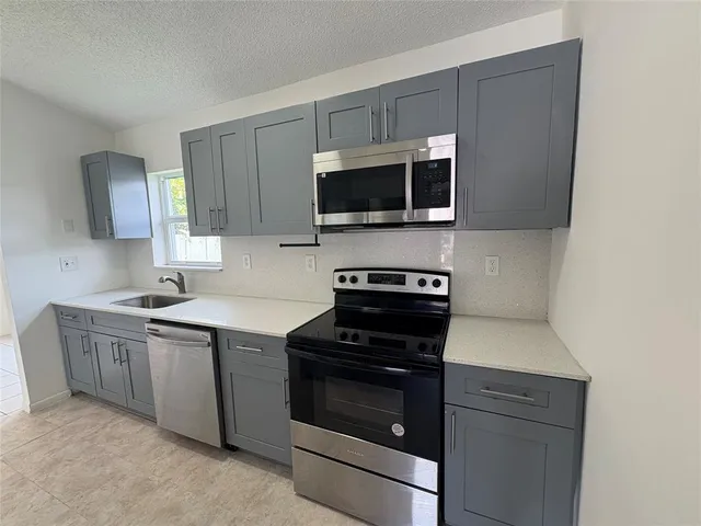 a kitchen with stainless steel appliances a stove microwave and sink