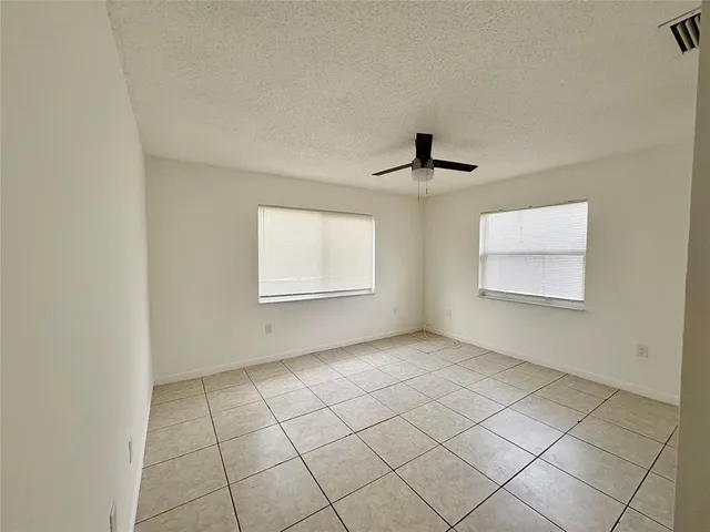 an empty room with windows and ceiling fan