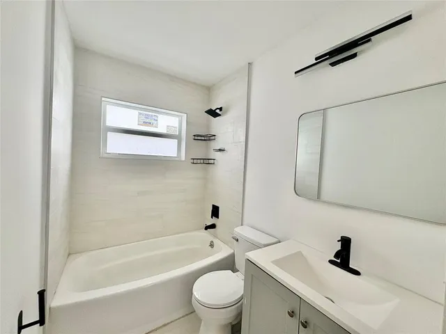 a bathroom with a bathtub shower sink vanity and toilet