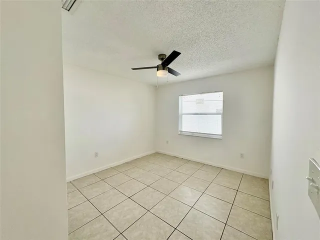 an empty room with windows and ceiling fan